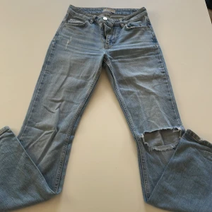Ljusblå bootcut jeans med hål - Säljer ett par ljusblå bootcut jeans från Perfect Jeans. De har mid midja, klassisk femficksdesign och ett hål på ena knät, avslappnad vibe. Jeansen är i mjukt denimtyg och har en snygg, rak passform upptill som går ut nertill.