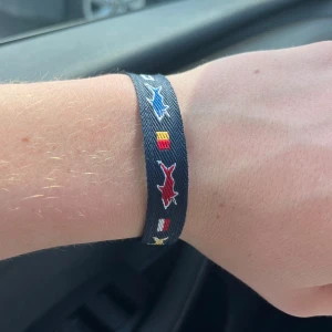 Sommar-armband - Snyggt marinblått armband med broderade färgglada signalflaggor och hajmotiv i rött, blått, gult och vitt. Justerbar knytning för perfekt passform. Perfekt accessoar för dig som gillar havet och vill sticka ut med coola detaljer.