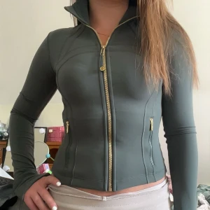 Define jacket från Lululemon - Snygg mörkgrön define jacket från Lululemon med guldig dragkedja och guldiga detaljer. Jackan är i storlek 2 som är samma sak som xs. Har sparsamt använt jackan så den är som ny! Vid eventuella fråger elelr fler bilder är det bara att kontakta mig!!🫶🫶
