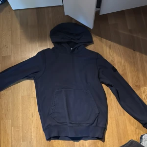 Mörkblå hoodie från Stone Island Junior - Säljer en mörkblå hoodie från Stone Island Junior. Nästan helt ny utan några defekter alls, denna tröja passar även XS!