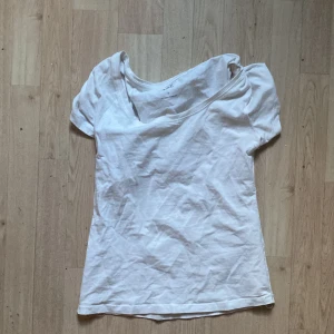 Vit offshoulder topp i bomull - Enkel vit topp med offshoulder-design och korta ärmar. Gjord i mjuk bomull, perfekt för en avslappnad och stilren look. Passar till jeans eller kjol för en fräsch vibe.