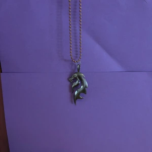 Halsband med lejonberlock i silverfärg - Coolt halsband med en silverfärgad lejonberlock i tribal-stil. Kedjan är av kulkedjemodell och ger ett edgy intryck. Perfekt för dig som vill sticka ut med ett unikt smycke med djurmotiv.