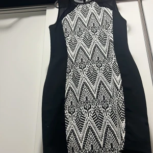 Svartvit mönstrad kort klänning Divided - Snygg svartvit kort klänning från Divided med grafiskt mönster framtill och meshdetaljer vid axlarna. Ärmlös modell med figurnära passform och rund halsringning. Perfekt för dig som gillar att sticka ut med coola kontraster och unika detaljer. Passar väldigt tight och snyggt på! Passar då M men också L