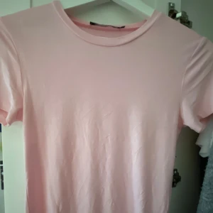 Ljusrosa basic t-shirt - Enkel och stilren ljusrosa t-shirt med rund halsringning och korta ärmar. Perfekt för en clean och avslappnad look. T-shirten är i mjuk bomull och har en klassisk passform som funkar till det mesta.