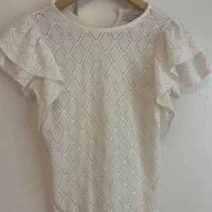 Vit blus med volangärm från Lindex - Supersöt vit blus med volangärmar och snyggt strukturmönster i tyget. Blusen har rund halsringning och liten knapp i nacken. De två sista bilderna är från tjejen jag köpte av då den inte passade mig! Men skriv för intresse eller frågor🥰