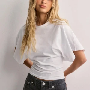 Vit croppad t-shirt med loose fit Nelly - Säljer en stilren vit t-shirt med croppad passform och breda, korta ärmar. T-shirten har en klassisk rund halsringning och är tillverkad i mjuk bomull. Perfekt för en avslappnad och trendig look.☺️nypris 299 kr🩷