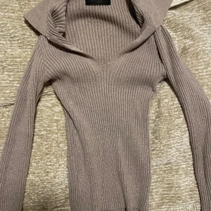 Beige ribbad stickad polotröja - Beige ribbad polotröja med lång ärm och figurnära passform. Tröjan har en djup v-ringning och är ifrån Shein i XS💕