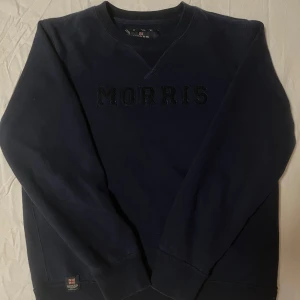 Mörkblå sweatshirt från Morris - En snygg mörkblå sweatshirt från Morris. Med den stora texten kan du lugnt gå på stan och samtidigt visa din ”aura”. Tröjan är använd nån enstaka gång och har inga hål eller liknande, så uppskattar att konditionen ligger på runt 8/10. Tröjan är storlek M men passar förmodligen även S! Vid övriga frågor så kontakta mig gärna, prisförslag uppskattas!🤗 Nypris: 1200kr