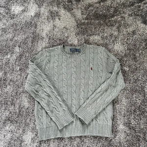 Ralph Lauren kabelstickad tröja - Grymt snygg och sällsynt kabelstickad grå tröja från Polo Ralph Lauren. Perfekt för svensk sommar. Nypris 2400kr. Hör av er vid minsta fundering!