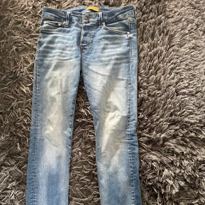Blå Glenn jeans från Jack & Jones 30/30 - Snygga ljusblå jeans från Jack & Jones, modell Glenn. , smal passform och snygga slitningar framtill. Perfekta för dig som gillar en modern och stilren look.