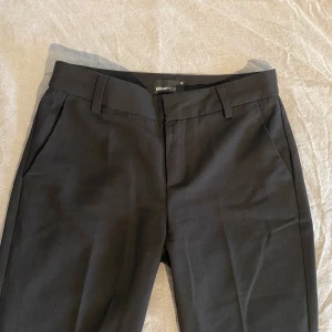 Svarta utsvänga kostymbyxor från Gina Tricot  - Säljer ett par svarta utsvängda kostymbyxor ifrån Gina tricot. Byxorna är en del använda men är ändå i bra skick. Det går att stänga med en dragkedja samt en hake och en extra knapp. De är i storlek 32, pris kan diskuteras. Hör gärna av er vid frågor eller funderingar💞💞