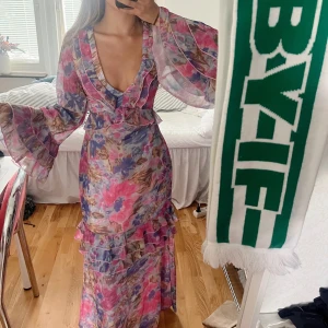 Blommig maxiklänning med volang - Helt oanvänd, endast testad med prislappen kvar. Köptes för 650kr inkl frakt och tull. Klänningen är: - Blommig, -figursydd i midjan, -volang, -vida ärmar. 