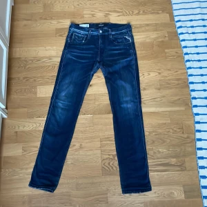 Blå jeansbyxor från Replay - Snygga blå jeansbyxor från Replay i modellen Anbass. De har en slim fit och är tillverkade i ett stretchigt material för extra komfort. Klassisk femficksdesign med dragkedja och knapp. Perfekta för en stilren look. W30 L32