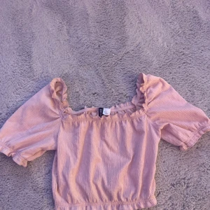 Rosa blus från hm - Säljer en söt rosa blus från HM med volangdetaljer. Blusen har korta puffärmar.