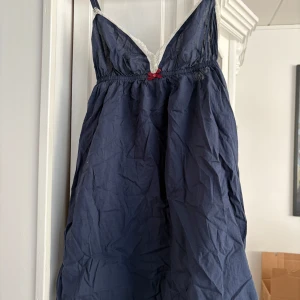 Marinblå klänning från Odd Molly - Säljer en söt marinblå klänning från Odd Molly med spetsdetaljer vid axelbanden och en liten rosett framtill. Klänningen har en avslappnad passform och är perfekt för varma dagar. Den har även en broderad detalj på baksidan. Storlek XS