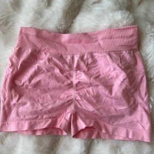 Rosa shorts - Säljer ett par söta rosa shorts med hög midja och ribbad detalj i midjan. Perfekta för en avslappnad dag eller träning. De är gjorda i ett mjukt och bekvämt material. Passar s också 
