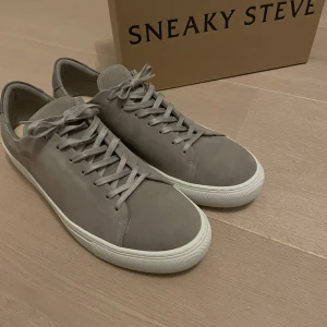 Grå sneakers från Sneaky Steve - Snygga grå sneakers från Sneaky Steve i mocka med klassisk snörning. Skorna är sprillans nya, har aldrig använt dom ute bara inne. Skorna är storlek 46. Perfekta sommar skor. 