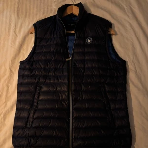 Sail Racing Väst - En stilren Sail Racing väst som passar perfekt till våren. Antingen under jackan för extra värme eller som ett snyggt ytterplagg.