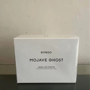 Byredo Mojave Ghost Absolu de Parfum - Säljer en Byredo Mojave Ghost Absolu de Parfum, 100 ml. Den kommer i en elegant vit förpackning med subtilt mönster och tydlig svart text. 