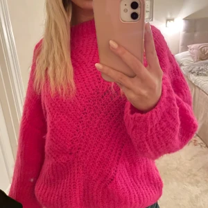 Rosa stickad tröja från Noella - Säljer en härligt rosa stickad tröja från Noella. Tröjan har en mysig och varm känsla med långa ärmar och en rund halsringning. Perfekt för att lysa upp din garderob!