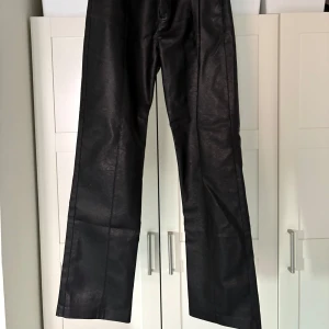 Svarta skinnbyxor från Gina Tricot - Snygga svarta skinnbyxor från Gina Tricot med en stilren design. Byxorna har en rak passform och hög midja, vilket ger en modern look. Perfekta för att ge din outfit en edgy touch.