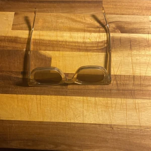 Transparenta solglasögon från Chimi - Snygga transparenta solglasögon från Chimi med fyrkantig form. De har en ljus toning på glasen och kommer i ett stilrent fodral. Perfekta för en trendig look.