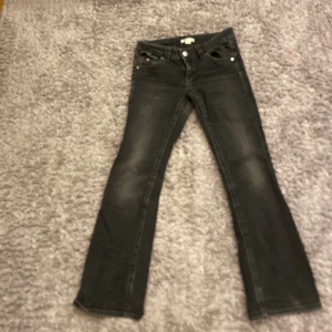 Svarta jeans från Gina Tricot - Snygga svarta jeans från Gina Tricot i storlek 158. De har en klassisk femficksdesign med knappar och dragkedja framtill. Perfekta för en stilren look.