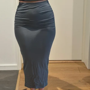 Grön långkjol - Snygg grön långkjol med tight passform. Kjolen har en stilren design och är perfekt för en elegant look. Den är tillverkad i ett mjukt och stretchigt material som ger en bekväm känsla hela dagen. Storlek xxs men passar även en xs.