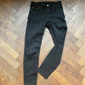 Svarta jeans från Acne  - Snygga svarta jeans från Acne med en klassisk design. De har en knappgylf och är tillverkade i Italien. Perfekta för en stilren look. 