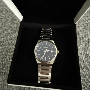  klocka Seiko - Säljer en elegant Seiko-klocka med en stilren silverfärgad länkarmband och en djupblå urtavla. Klockan har tydliga markeringar och datumvisning, perfekt för den som söker en klassisk och tidlös design. Jag säljer nu min seiko klocka då den inte kommer till användning de är en seiko classic den går för 4000 på ordinarie pris, klockan är i jättebra skick 9/10 och funkar utmärkt full presentation finns låda och allt det är en 40mm, hör gärna av dig för fler frågor(priset kan diskuteras)