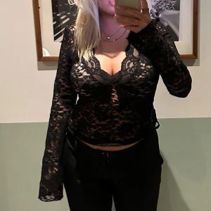 svart spetsblus - snygg svart spetsblus med långärmad design och v-ringad hals. perfekt för en elegant look med sina utsvängda armar och figursydda passform. använd en gång så precis som ny!!!