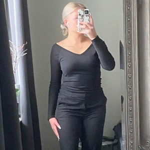 Svart långärmad topp - Snygg svart långärmad topp med v-ringning. Perfekt för en stilren look. Passar bra till både jeans och kjol.