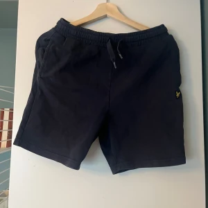 Svarta lyle & Scott  shorts med snörning - Snygga svarta shorts med elastisk midja och snörning. Perfekta för en avslappnad stil. Har en bakficka för extra funktionalitet. Pris kan diskuteras 