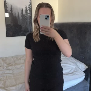 Svart kortärmad topp - Säljer en stilren svart kortärmad topp med en tight passform. Perfekt för en minimalistisk look. Toppen är enkel och har en liten krage.