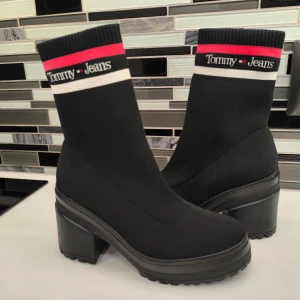 Svarta boots från Tommy Jeans - Snygga svarta boots från Tommy Jeans med en ribbad överdel och märkets logga i rött och vitt. Skorna har en robust klack och en bekväm passform. Perfekta för att ge din outfit en stilren touch. använda flera gånger, nästan nya.