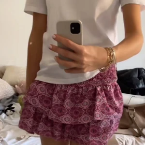 Rosa mönstrade shorts - Snygga rosa shorts med ett unikt mönster och volangdetaljer. Perfekta för en somrig look. De har en elastisk midja för extra komfort.