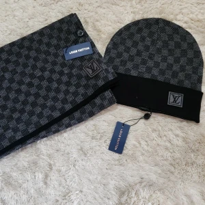 Rutig mössa  - Snygg rutig mössa  i svart och grått. Tillverkad i en blandning av ull och siden för en lyxig känsla. Mössan har en diskret logotyp framtill och passar perfekt för kyligare dagar.