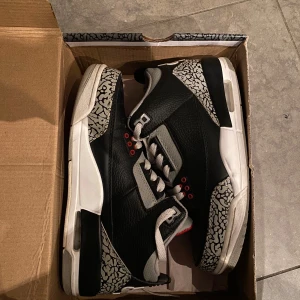 Nike Air Jordan 3 Retro - Säljer ett par klassiska Nike Air Jordan 3 Retro sneakers i svart, grått och rött. Skorna har den ikoniska elefantmönstret och Nike Air-loggan på hälen. Perfekta för sneakerheads som älskar retrostil! Osäker på äktheten därav priset! Skriv vid funderingar eller fler bilder!