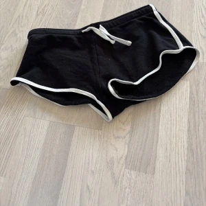 Svarta shorts med vita detaljer - Snygga svarta shorts med vita kanter och snörning i midjan. Perfekta för en avslappnad stil.