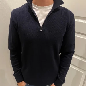 Mörkblå tröja med dragkedja - Snygg mörkblå tröja med dragkedja och hög krage. Perfekt för kyligare dagar. Tröjan har långa ärmar och en stilren design som passar till det mesta.