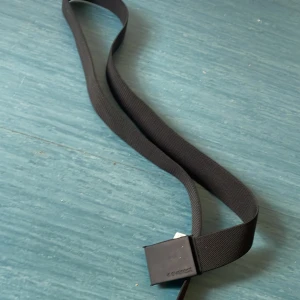 Svart tygbälte med metallspänne - Säljer ett svart tygbälte från Everest  med ett stilrent, fyrkantigt metallspänne. Perfekt för dig som vill ha en enkel och clean look till jeans eller chinos. Bältet är justerbart och passar de flesta midjemått. Endast kontant hämtas i Västerhaninge 