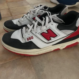 New Balance 550 sneakers i vitt, svart och rött - Säljer ett par New Balance 550 sneakers i vitt, svart och rött.