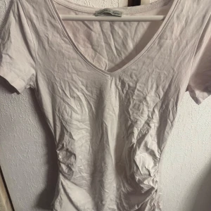 Vit v-ringad t-shirt från Anna Field  - Säljer en enkel och stilren vit t-shirt från Anna Field Mama. T-shirten har v-ringning och korta ärmar, perfekt för en avslappnad look. Tillverkad i mjuk bomull som känns skön mot huden.