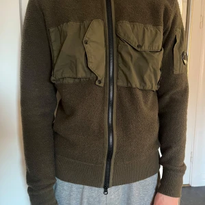 Grön cardigan jacka från C.P. Company - Säljer en stickad cardigan jacka från C.P. Company! Den är i storlek 48 och är använd 3 gånger! Jag är 178 cm lång!Inga defekter och kvitto finns! Ny pris 4800kr! Hör gärna av er vid frågor(: Priset är diskuterbart