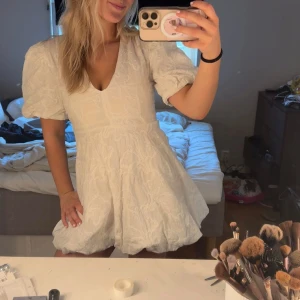 Vit kortklänning med puffärmar och strukturmönster - Superfin vit kortklänning. Säljer då den tyvärr sitter för tajt på mig. Perfekt inför student eller allmänt inför sommaren💕