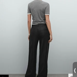 Svarta vida linnebyxor - Snygga svarta linnebyxor med hög midja och vida ben. Byxorna har en klassisk passform med diskreta fickor i sidorna och slät front. Perfekta för en stilren och avslappnad look. I nyskick och aldrig använda.