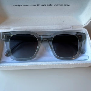 Gråa solglasögon från Chimi - Snygga solglasögon från Chimi i transparent grått acetat med mörka glas. Rektangulär form och diskret logga på skalmen. Perfekta för att lyfta din stil med en modern touch.