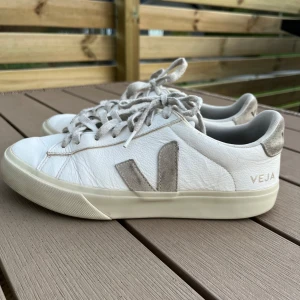 Vita sneakers från Veja med beiga detaljer - Vita sneakers från Veja med beiga mockadetaljer. Lite slitna på den sidan som är inåt (se bild). Storlek 40