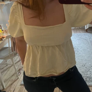 Ljusgul blus med volang - Söt ljusgul blus med fyrkantig ringning och korta puffärmar. 