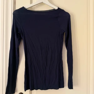 Mörkblå långärmad topp - En enkel och stilren mörkblå långärmad topp med rund halsringning. Perfekt att matcha med jeans eller kjol för en clean look. Tunn och mjuk i materialet, passar bra till lager-på-lager. 